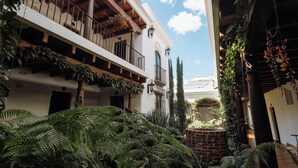 Un bâtiment doté d’un balcon, de plantes en pot et d’un mur en briques.