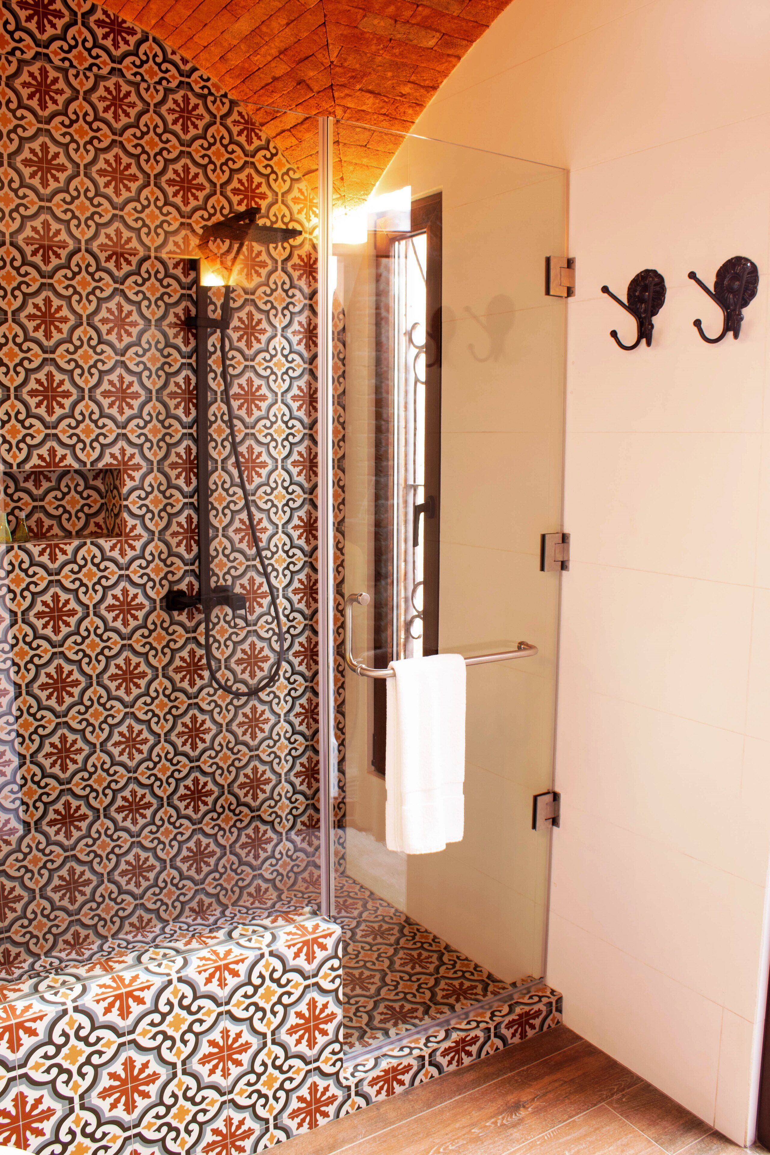 A bathroom with patterned tiles, a glass shower enclosure, and a towel rack.