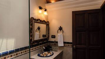 Un baño con un espejo grande, un lavabo con una pila decorativa, un perchero y una puerta.