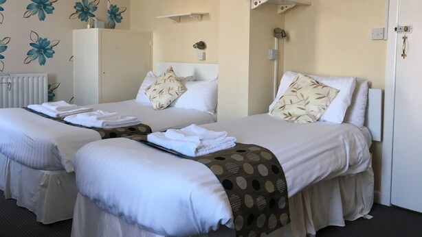A hotel room with two beds, a radiator, a mirror, and a wall with a floral pattern. - The Address (Blackpool)