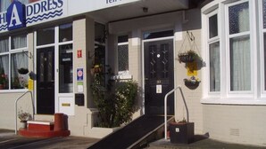 A building with a black door, a ramp leading to the entrance, and a sign indicating 'Vacancies'. - The Address (Blackpool)