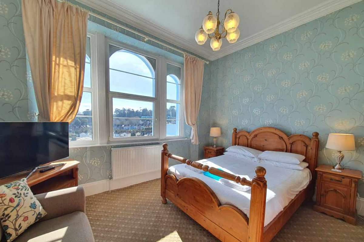 A bedroom with a large bed, a television, and a view of a cityscape through a window.