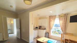 A compact living space with a kitchenette, a dining area, and a sofa. - The Purple Tree Guest House (Torquay)