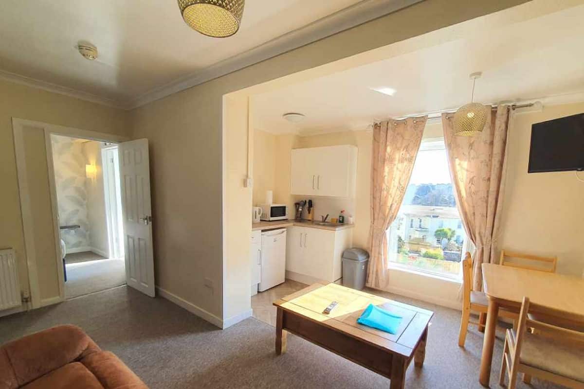 A compact living space with a kitchenette, a dining area, and a sofa.