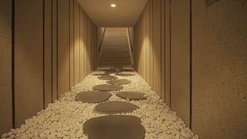 Un pasillo con un sendero de piedra y una escalera que sube a un nivel superior.