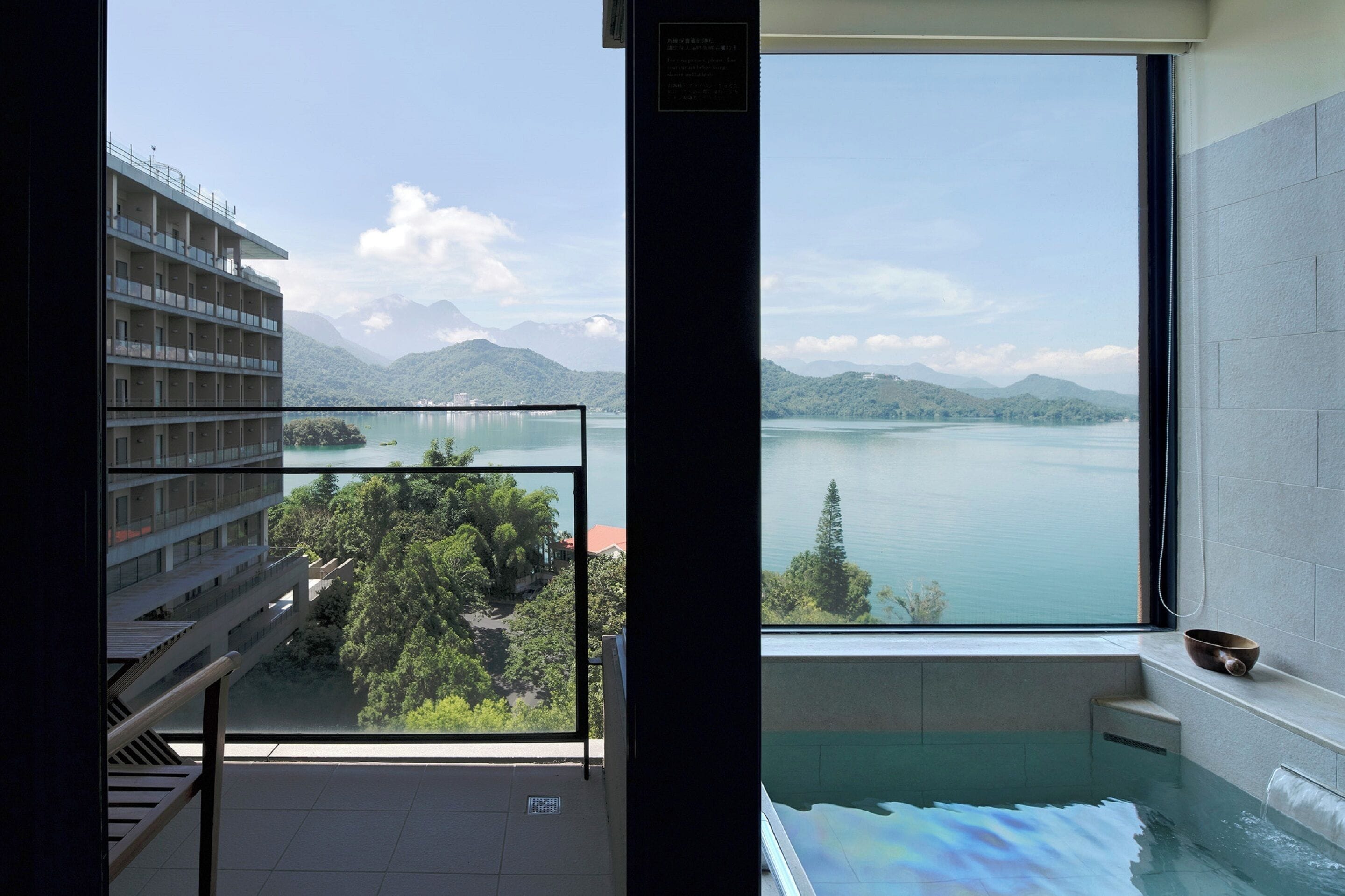 Ein modernes Hotelzimmer mit großem Fenster und Blick auf einen See und Berge.