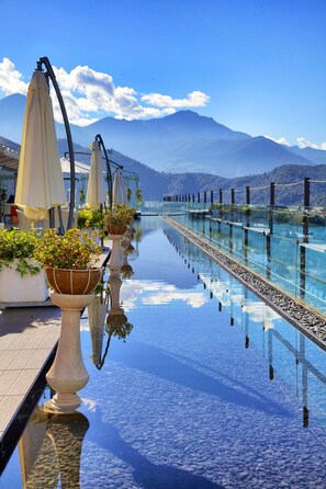 A long, reflective pool with potted plants and umbrellas, overlooking a mountain range. - Fleur de Chine Hotel (Yuchi)