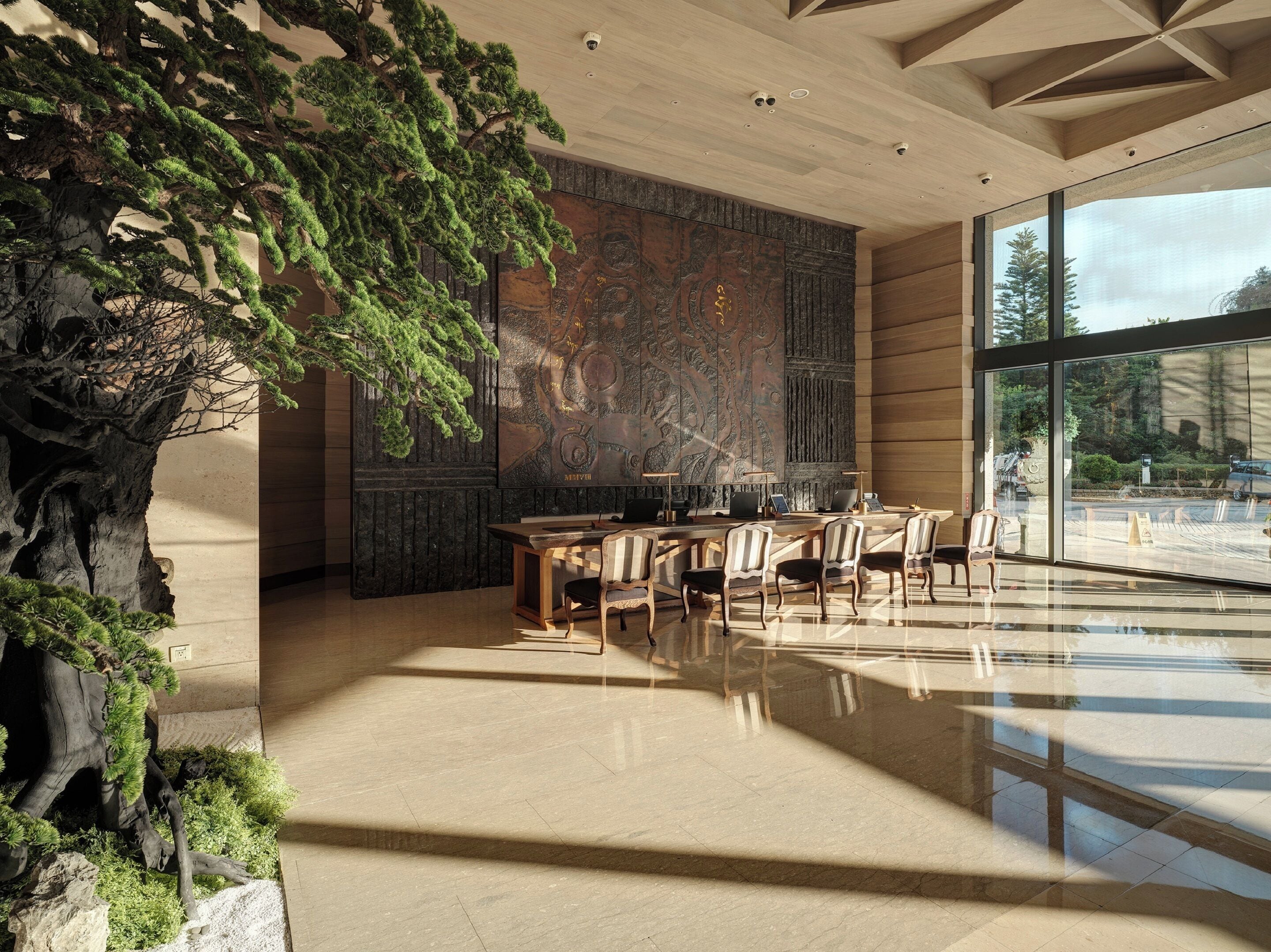A modern interior with a large glass window, a wooden reception desk, and a wall-mounted map.