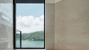 Uma casa de banho moderna com uma janela grande, uma banheira e uma tigela de madeira no balcão.