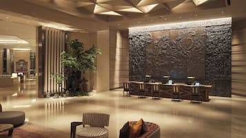 A modern lobby with a reception desk, seating area, and a decorative wall.