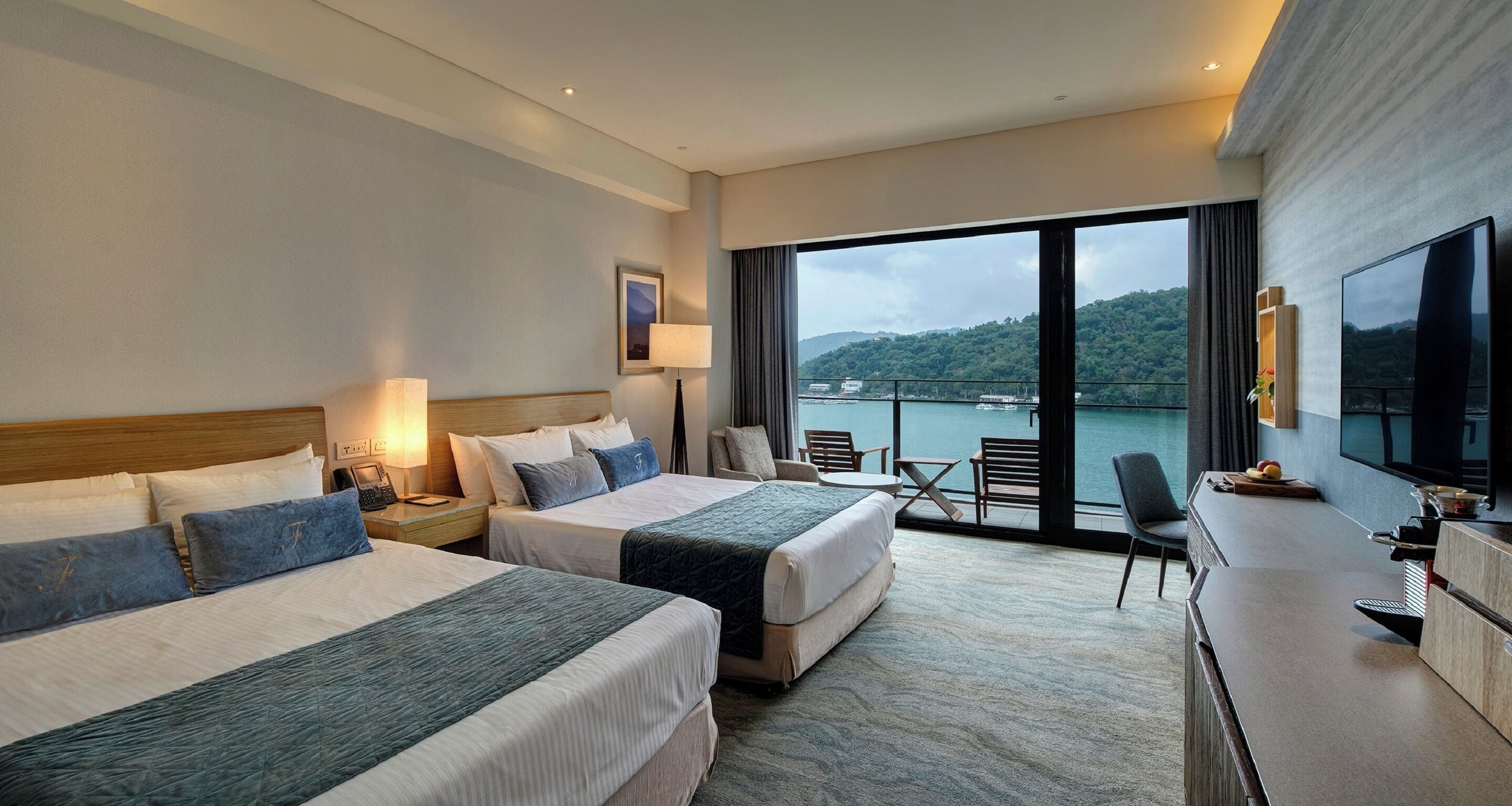 Habitación de hotel con dos camas, un escritorio, televisión y vistas a un cuerpo de agua.