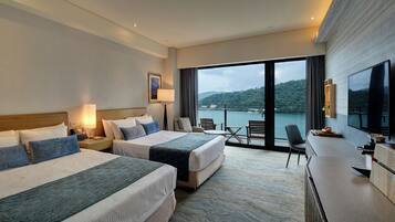 Habitación de hotel con dos camas, un escritorio, televisión y vistas a un cuerpo de agua.
