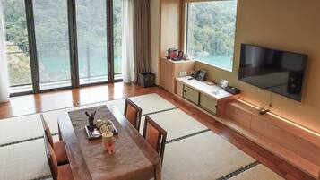 Ein modernes Zimmer mit einem Holzespeisetisch, Tatami-Matten, einem Fernseher und einem Balkon mit schöner Aussicht.