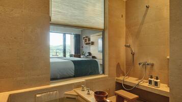 A modern bathroom with a bathtub, a shower, and a window with blinds.