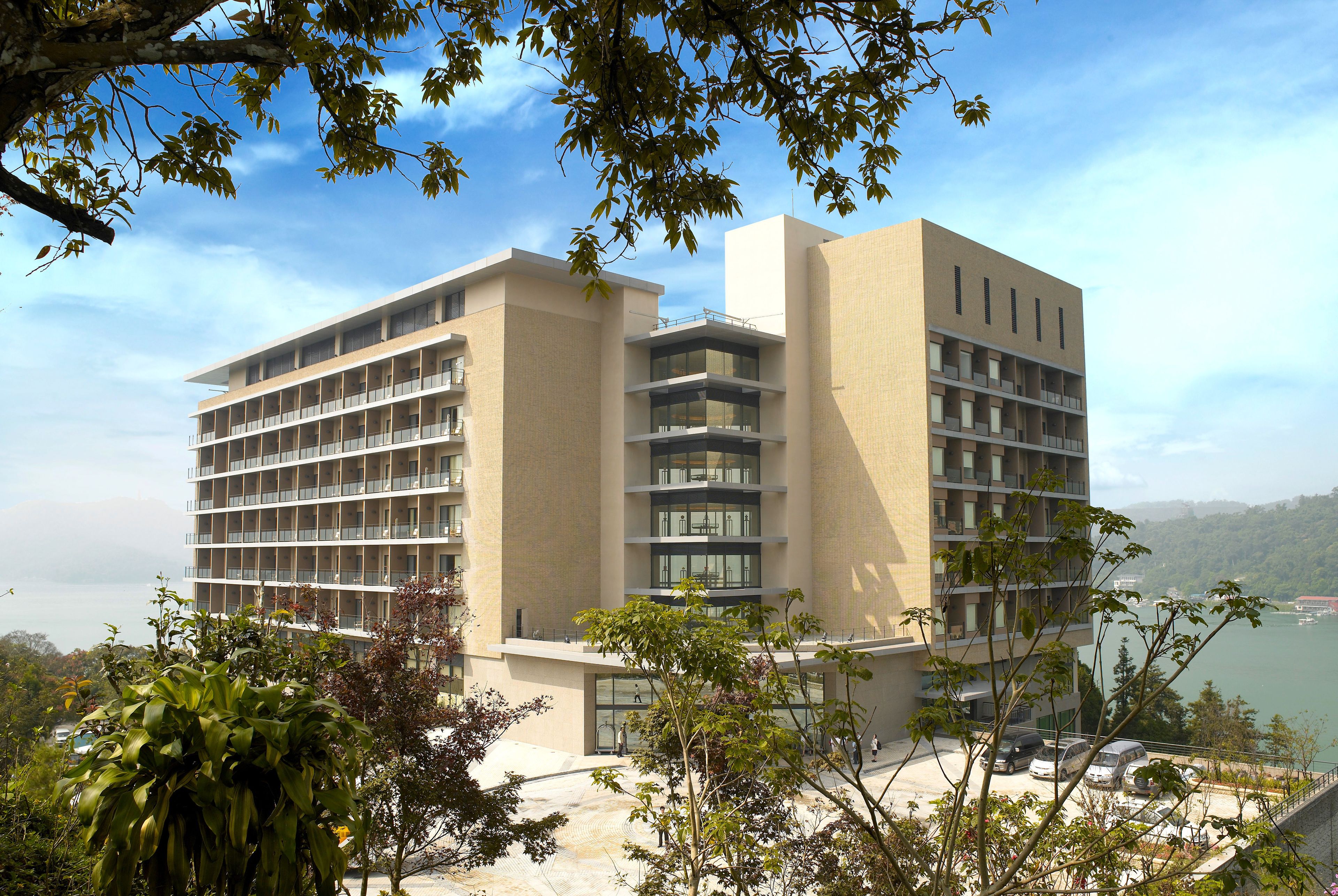 Un hôtel moderne à plusieurs étages, doté de balcons et offrant une vue sur un lac.