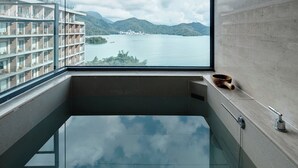 Um banheiro moderno com uma grande janela com vista para um lago e montanhas.