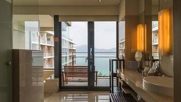 Een moderne badkamer met een grote spiegel, een badkuip en een bankje.