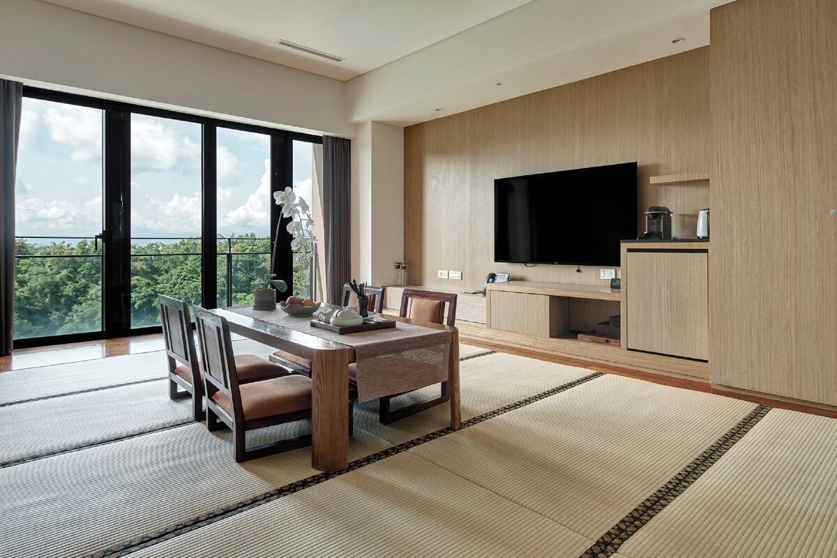 Una sala de estar moderna con una mesa de comedor, sillas, un televisor de pantalla plana y vistas al exterior.