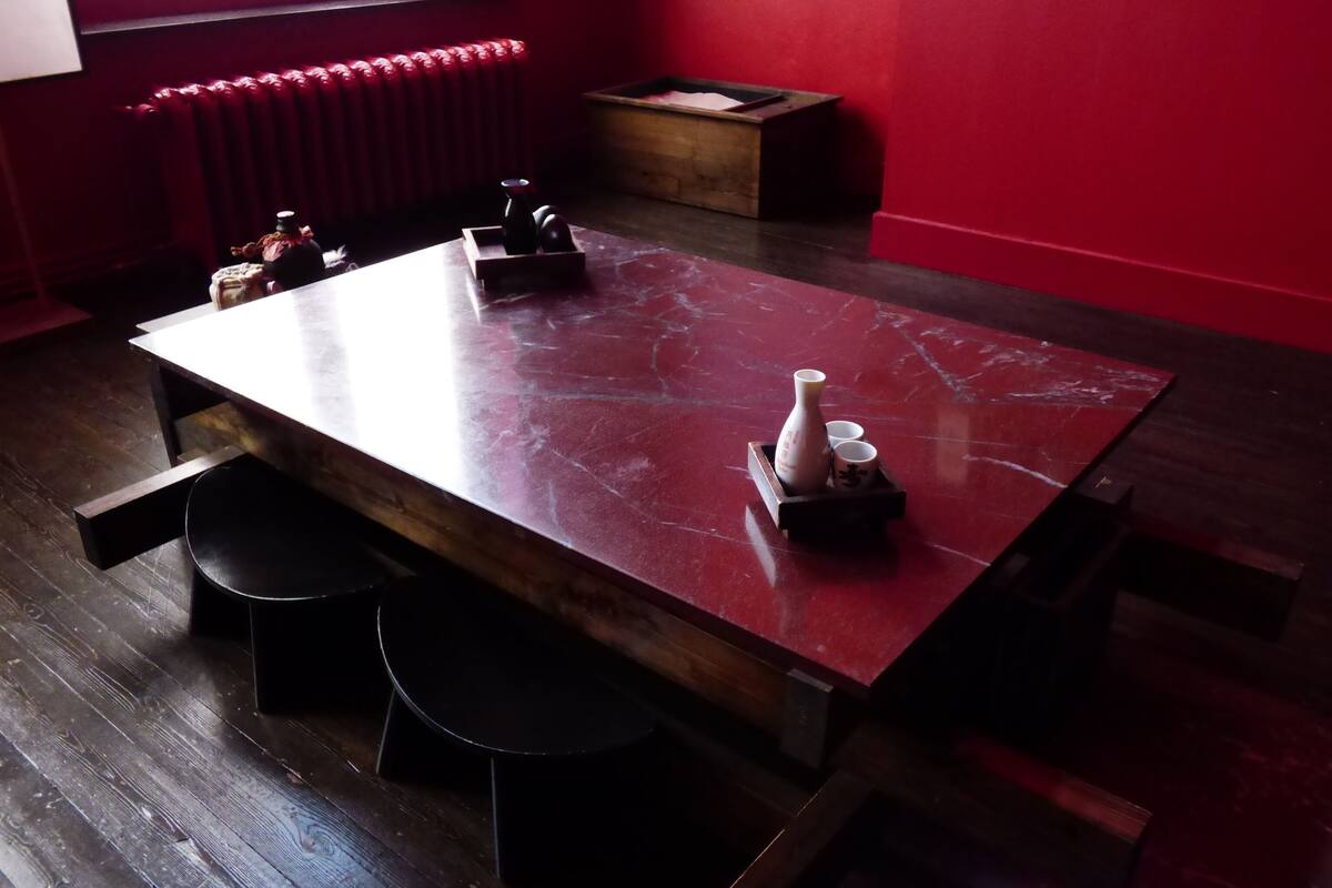 A room with a red marble table, black chairs, and a radiator.