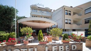 A hotel named "HOTEL LEBED" with an outdoor seating area, potted plants, and a covered patio. - Lebed (Ohrid)