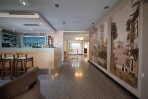 A hotel lobby with a bar area, seating, and a hallway leading to a room.