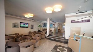 A reception area with a reception desk, seating area with sofas, and a TV on the wall.