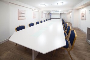 A conference room with a long table, blue chairs, and motivational posters on the walls. - Lebed (Ohrid)
