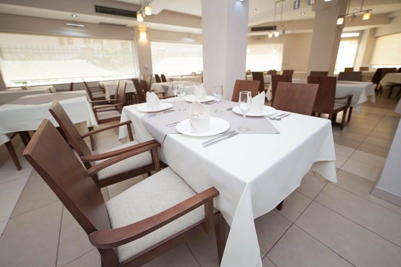A restaurant with white tablecloths, wooden chairs, and a bright interior.