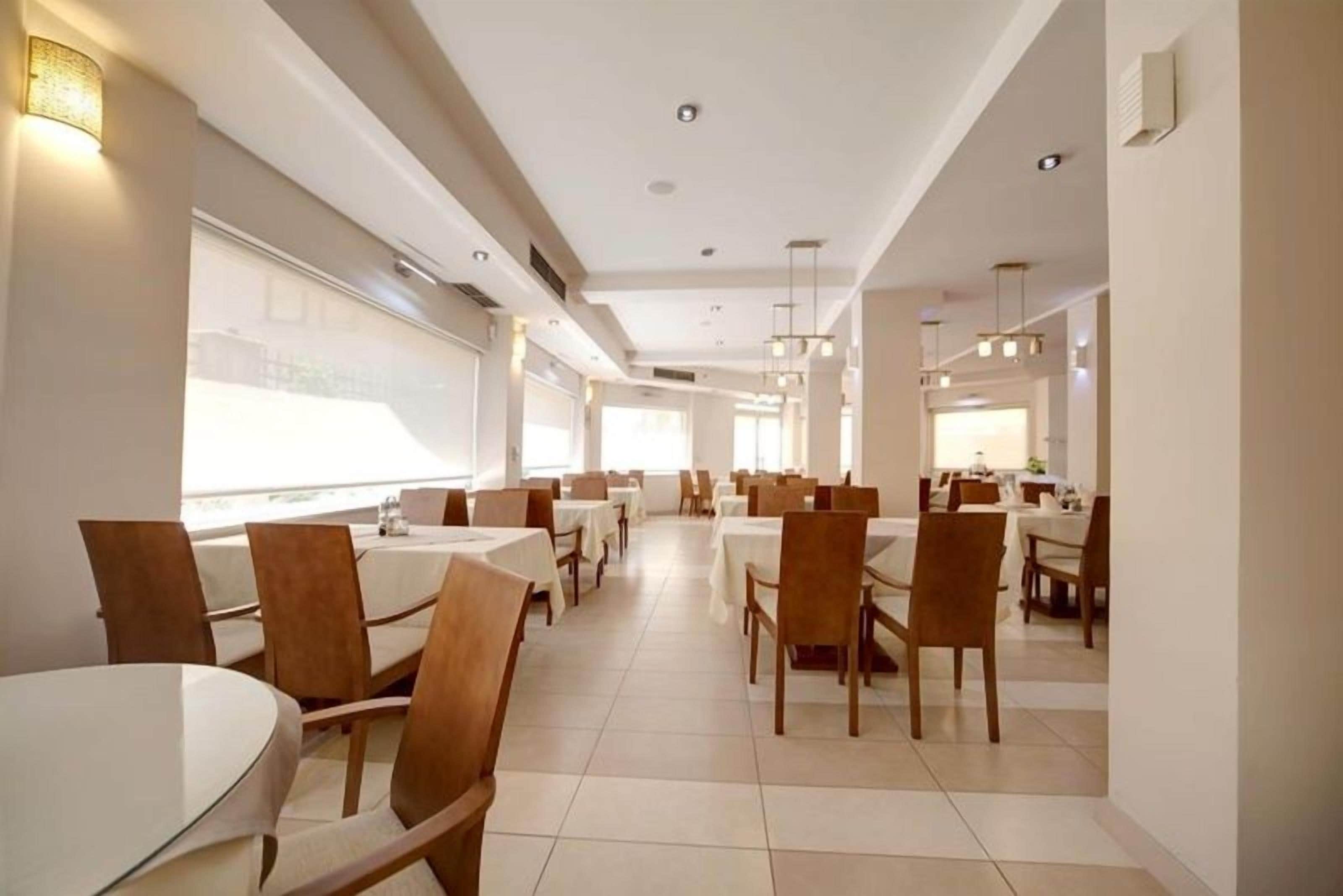 Un comedor moderno con mesas y sillas redondas, ventanas amplias e iluminación empotrada.