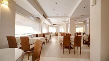 Un comedor moderno con mesas y sillas redondas, ventanas amplias e iluminación empotrada.