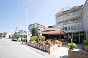 Hotel llamado 'HOTEL LEBED', con un área de estar al aire libre cubierta y plantas en macetas.