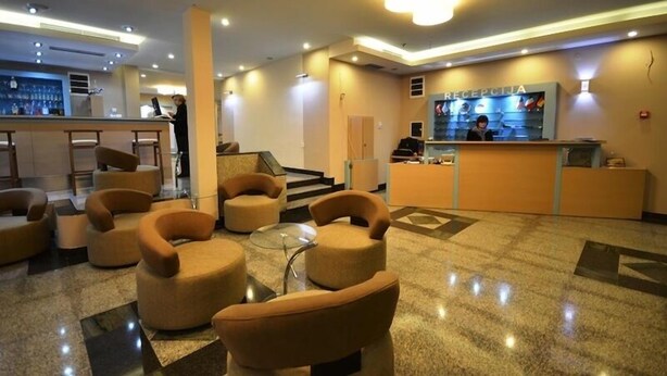 A hotel lobby with a reception desk, a bar area, and several seating options.