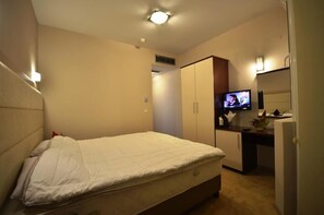 Una habitación de hotel con cama, televisión, escritorio y armario.