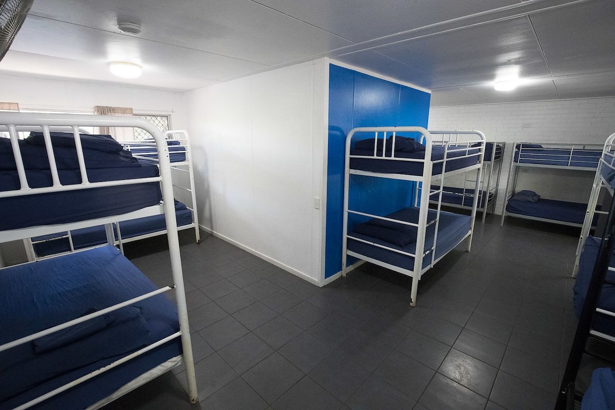 A dormitory room with bunk beds, a white door, and a tiled floor.