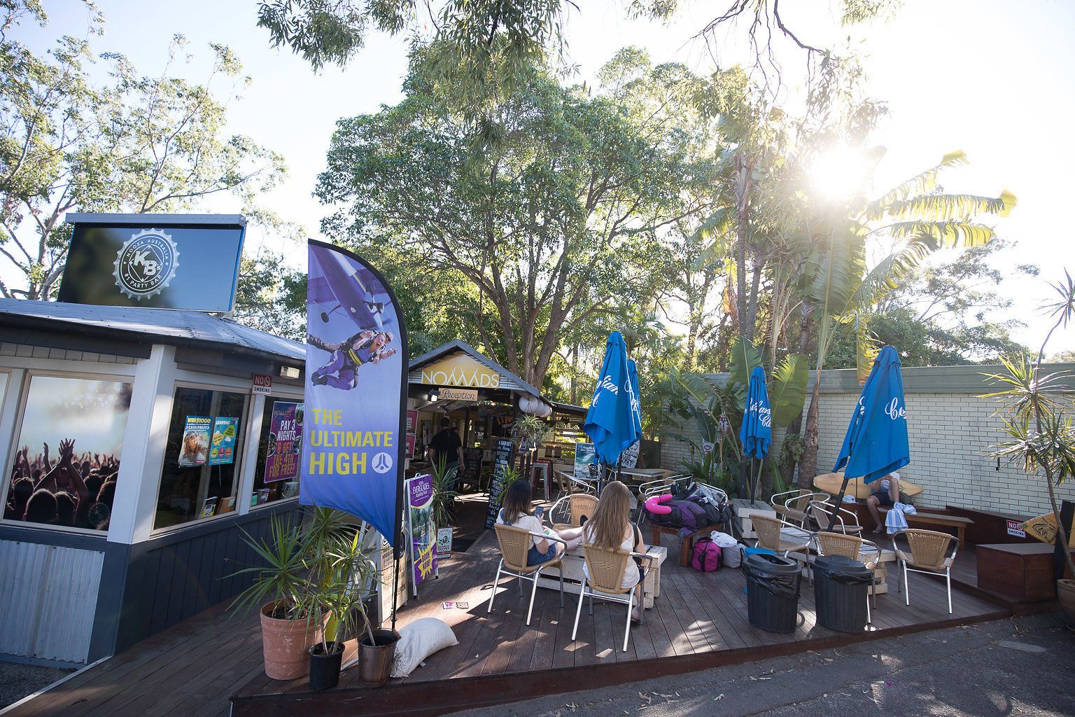 An outdoor seating area with tables and chairs, surrounded by potted plants and umbrellas.