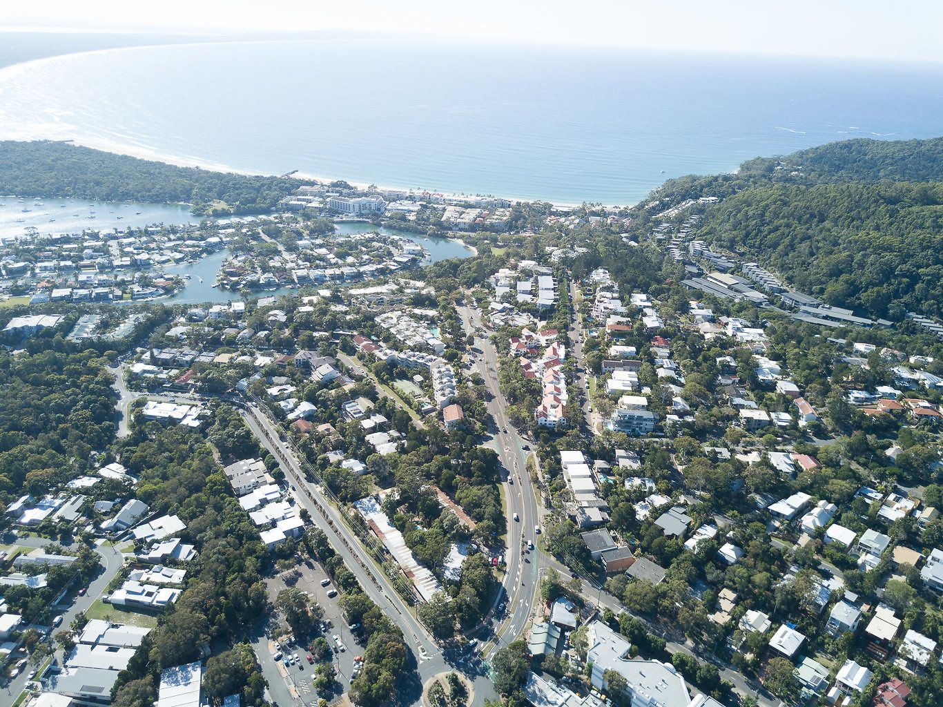 Vue aérienne d’une ville côtière avec des zones résidentielles, des routes et un port de plaisance.