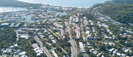Vue aérienne d’une ville côtière avec des zones résidentielles, des routes et un port de plaisance.