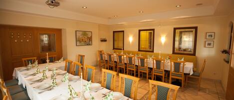 A dining area with multiple tables set for a meal, chairs, and a projector on the ceiling.