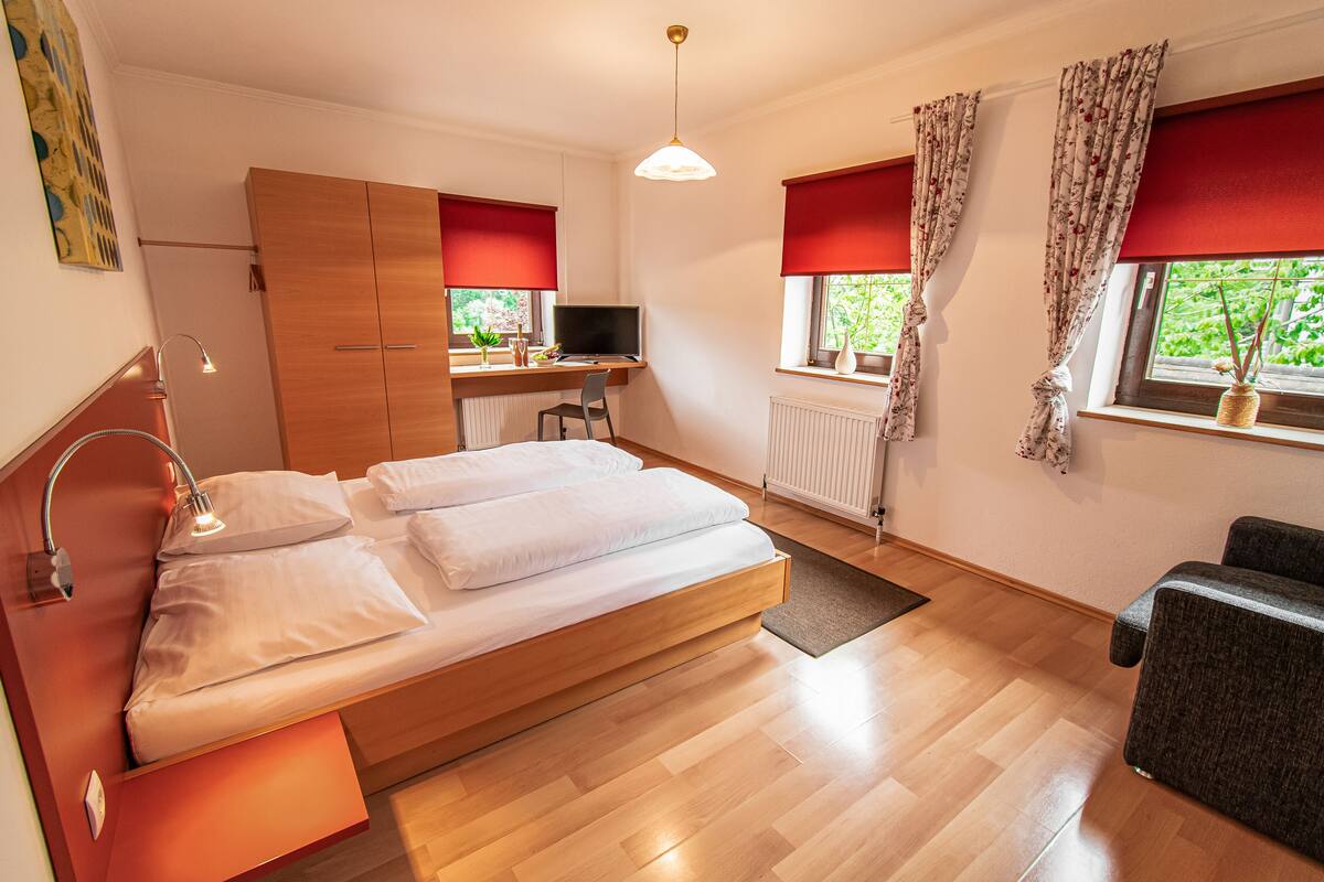 A modern bedroom with a wooden bed, a desk, a chair, and a TV.