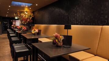 A restaurant with multiple tables and booths, each with a vase of flowers.