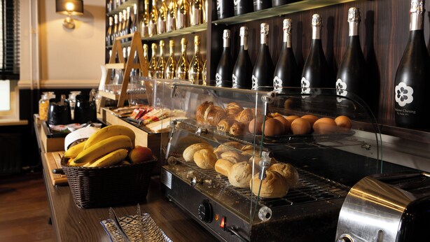 A bakery display with bread, croissants, and eggs, and a selection of wine bottles in the background. - Petit Nord (Hoorn)