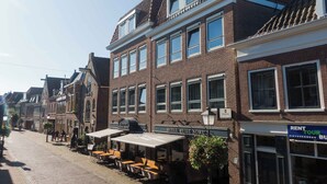A row of traditional European-style buildings with a brick facade, large windows, and a sign for "Hotel Petit Nord". - Petit Nord (Hoorn)