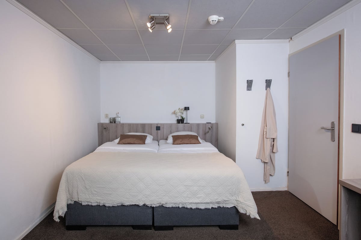 A neatly arranged bedroom with a bed, bedside tables, and a door.