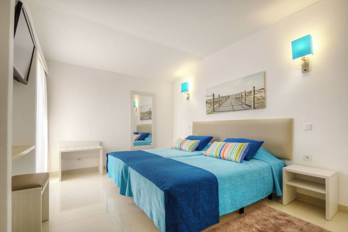Une chambre avec deux lits, un grand miroir et un tableau au mur.