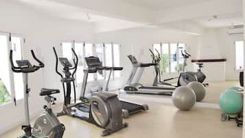 Ein Fitnessstudio mit verschiedenen Trainingsgeräten, darunter Laufbänder, Crosstrainer und Gymbälle.