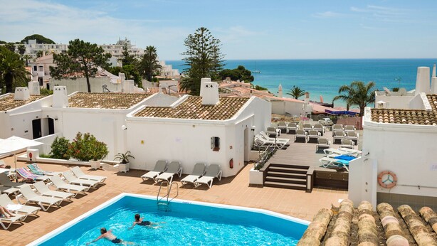 Una piscina en la azotea con sillones de descanso y vistas al mar.