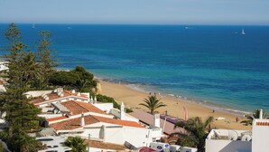 Un pueblo costero con una playa, edificios con tejas rojas y una vista despejada del mar.