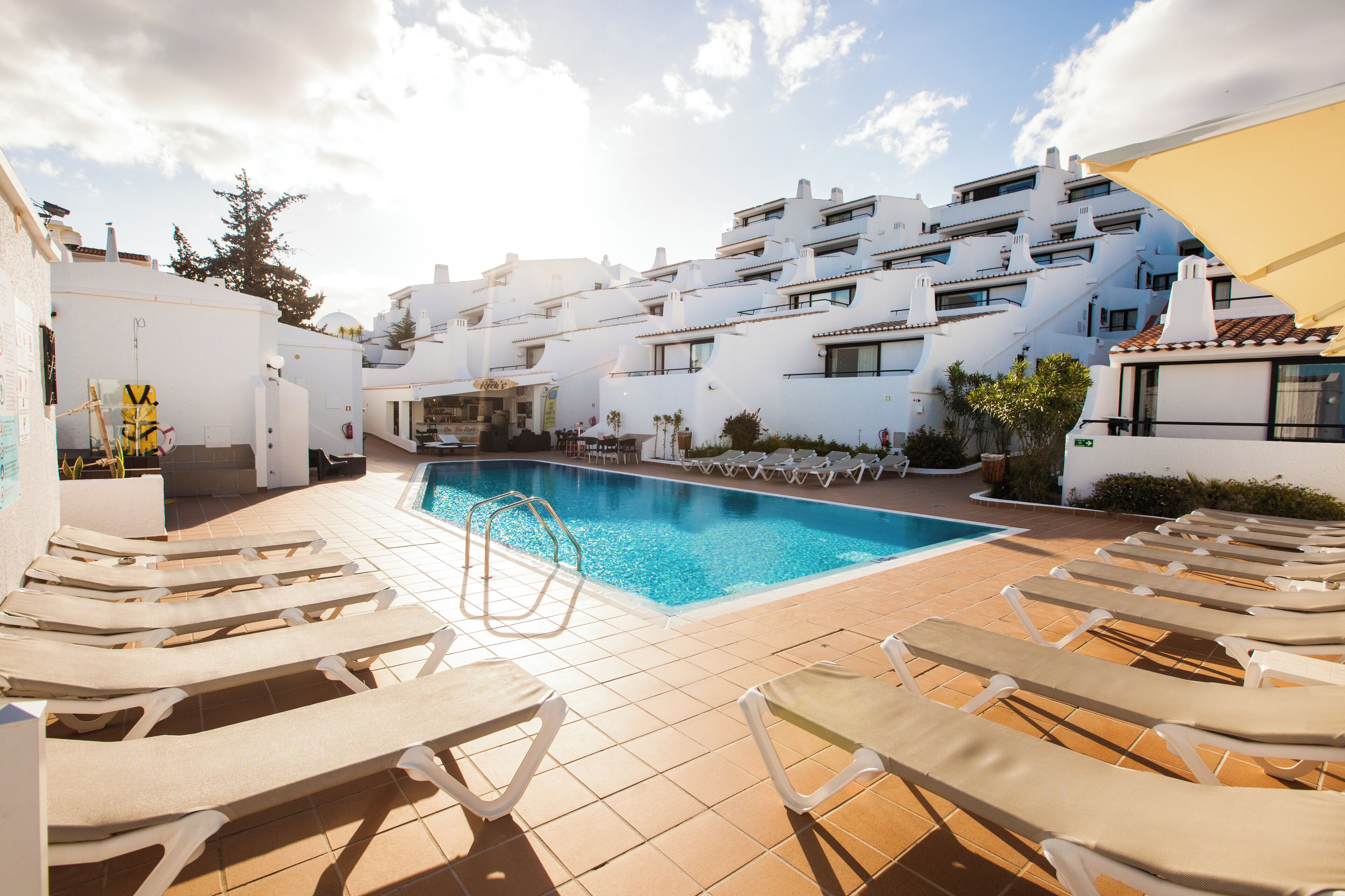 Un espace piscine avec des chaises longues et une terrasse carrelée.
