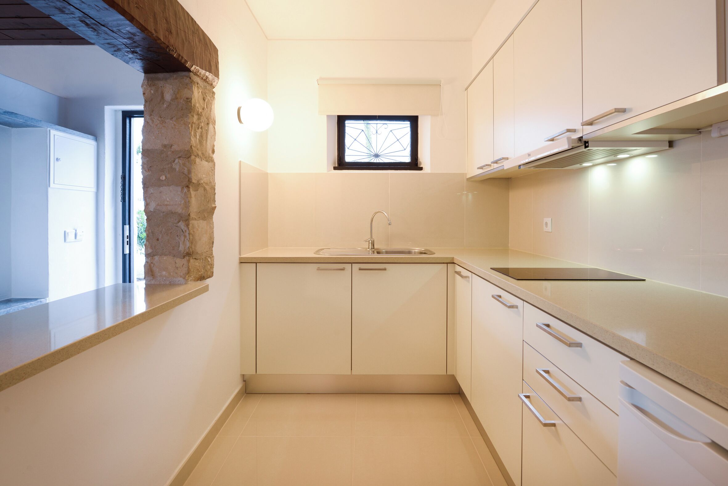 A modern kitchen with white cabinets, a built-in oven, and a window above the sink.