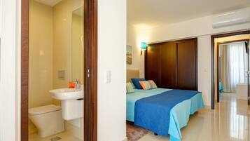 A bedroom with a bed, a bedside table, a wall-mounted lamp, and a wardrobe.